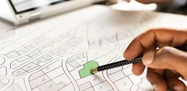 Person using a pencil to point at a property on a map, likely discussing real estate or planning. Person using a pencil to point at a property on a map, likely discussing real estate or planning.
